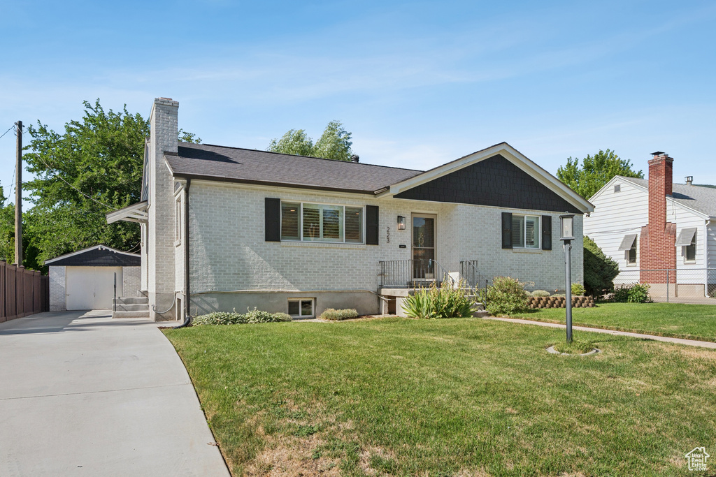 Ranch-style home with concrete driveway, brick siding, a garage, an outbuilding, and a chimney