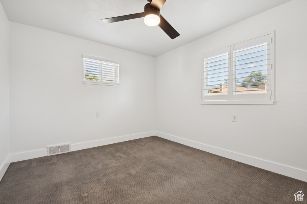 Unfurnished room featuring ceiling fan and dark colored carpet