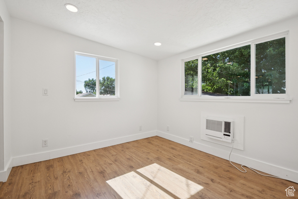 Spare room with wood finished floors, an AC wall unit, and recessed lighting