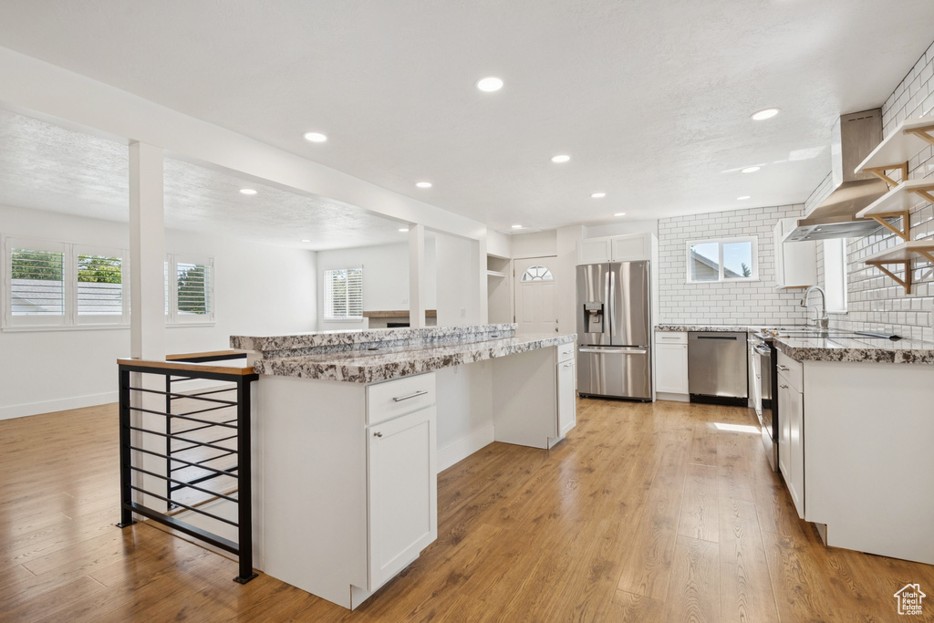 Kitchen with stainless steel appliances, a center island, light wood-style floors, a breakfast bar, and recessed lighting