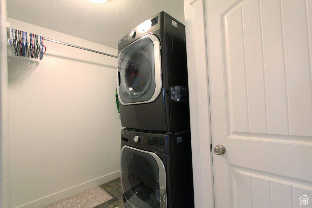 Washroom with stacked washing machine and dryer and baseboards