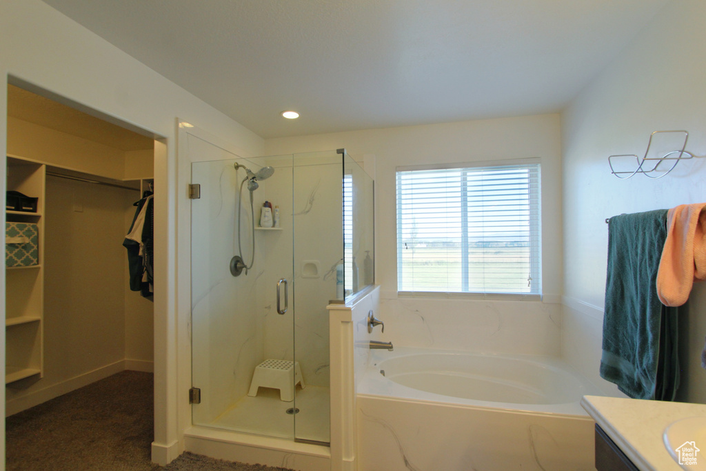 Full bath featuring a bath, a shower stall, vanity, a walk in closet, and recessed lighting