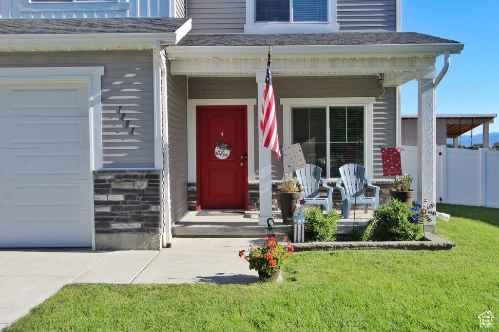 View of exterior entry with a porch, a shingled roof, and stone siding