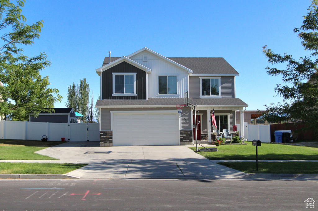 View of front of property featuring concrete driveway, an attached garage, stone siding, and a porch