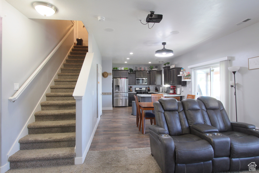 Living room with stairway, dark colored carpet, and recessed lighting