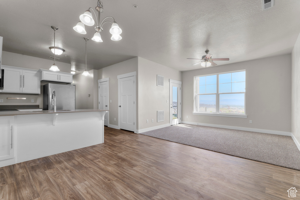 Kitchen featuring freestanding refrigerator, ceiling fan, white cabinetry, and open floor plan