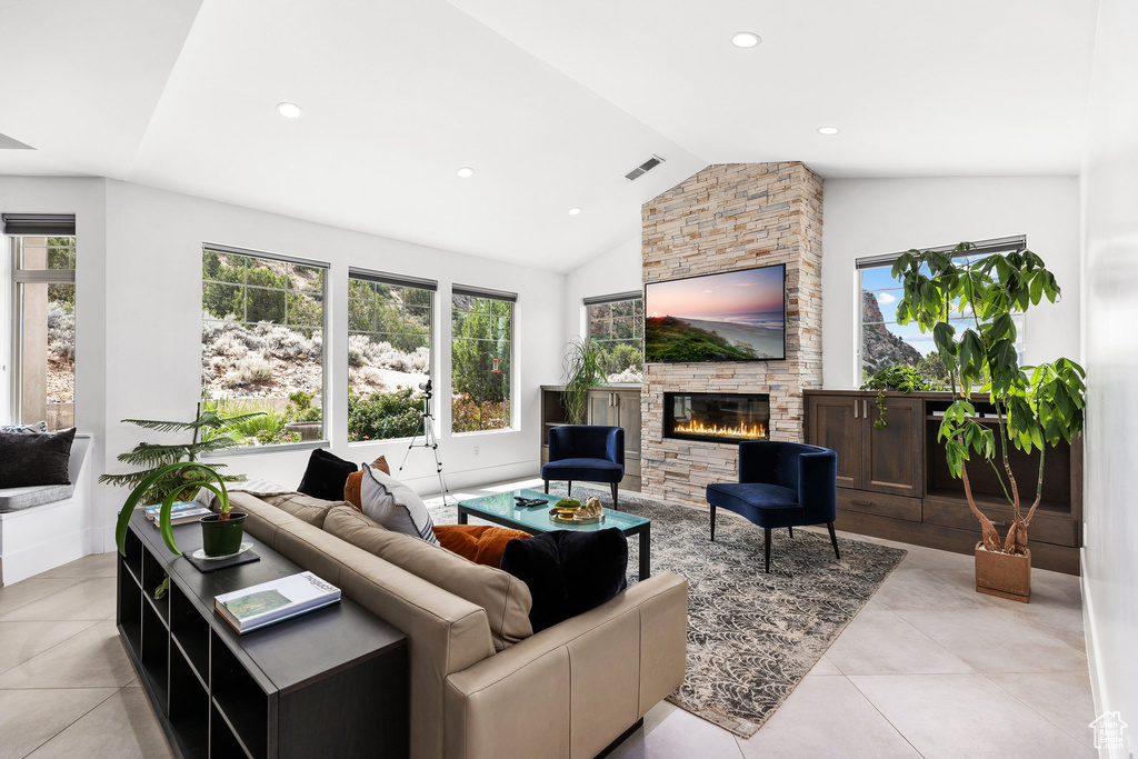 Living room with a stone fireplace, light tile patterned flooring, recessed lighting, and high vaulted ceiling