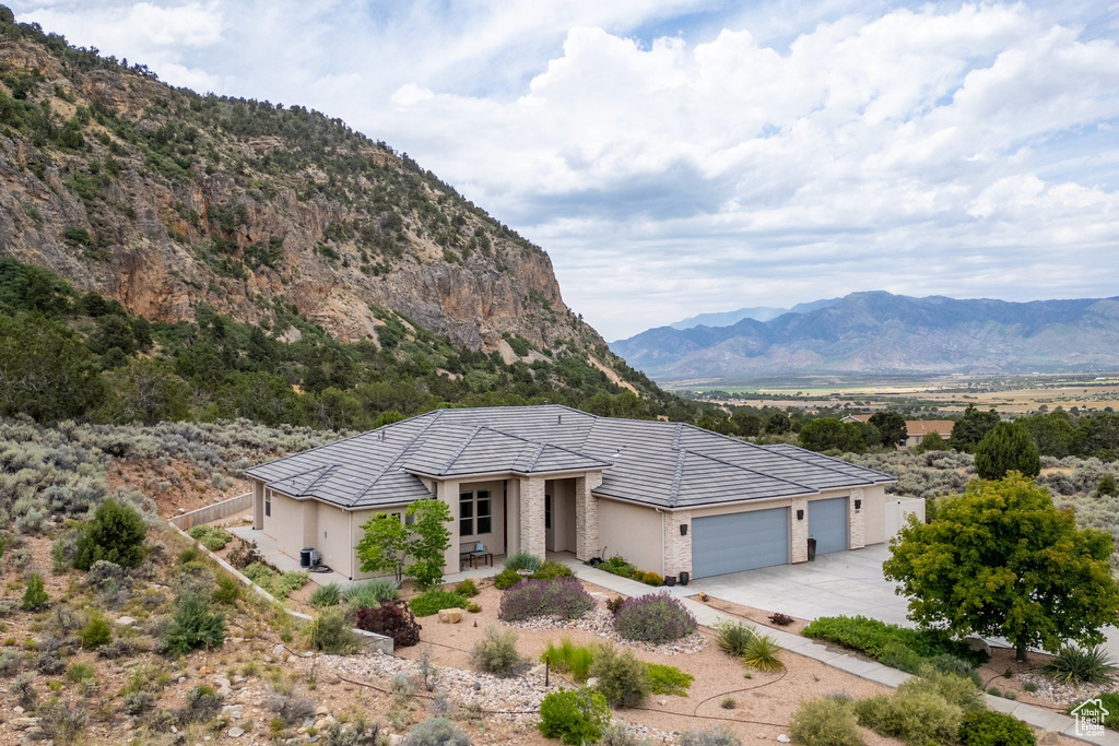 View of front of home featuring a mountain view, an attached garage, driveway, stucco siding, and a tile roof