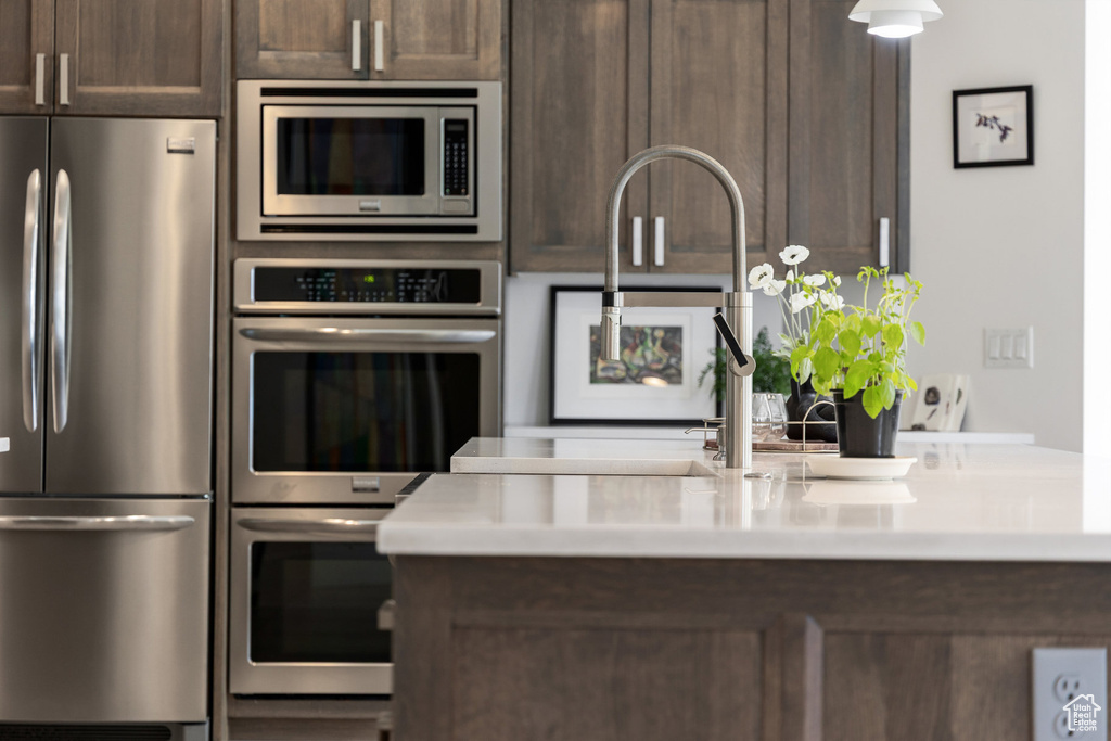 Kitchen featuring appliances with stainless steel finishes, dark brown cabinetry, and light countertops