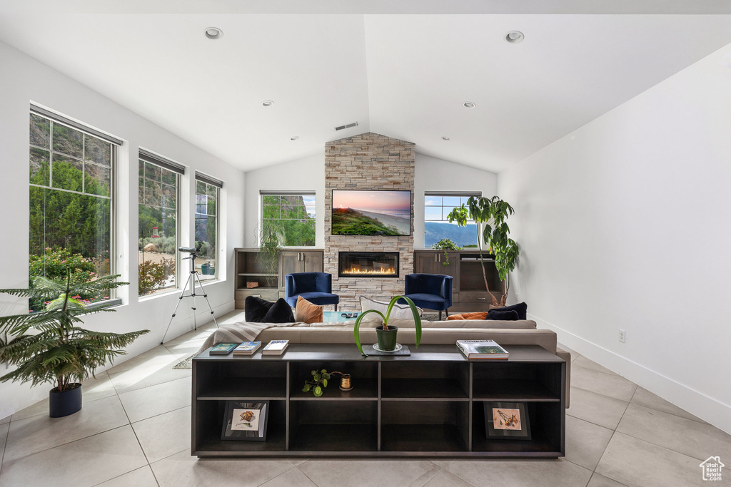 Living room featuring lofted ceiling, a fireplace, and light tile patterned floors