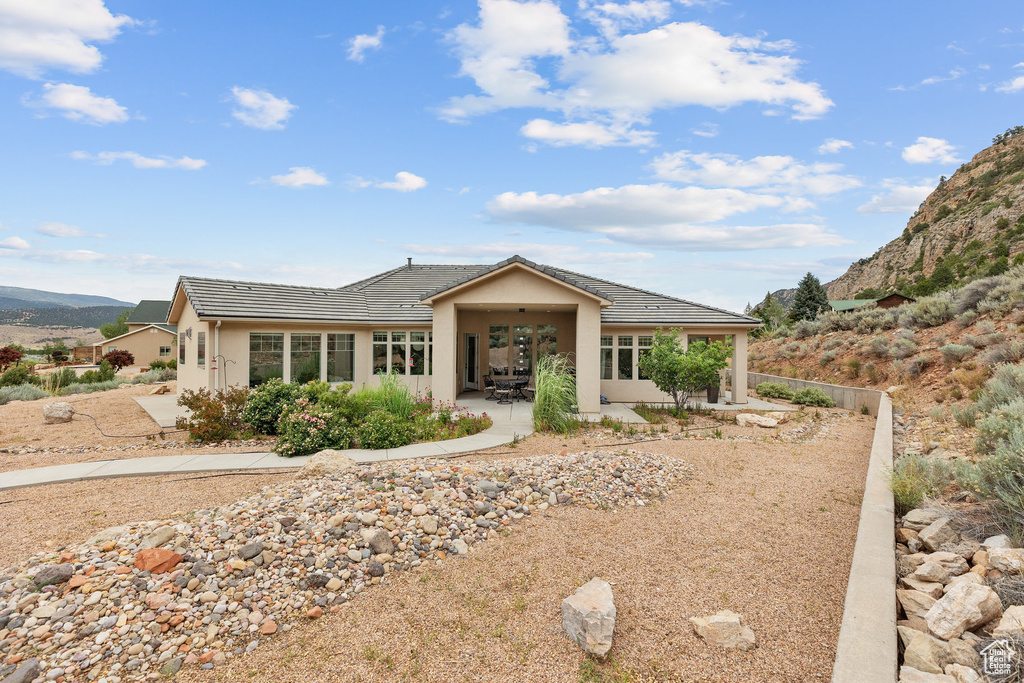 View of front of property featuring a patio area, a tile roof, a mountain view, and stucco siding