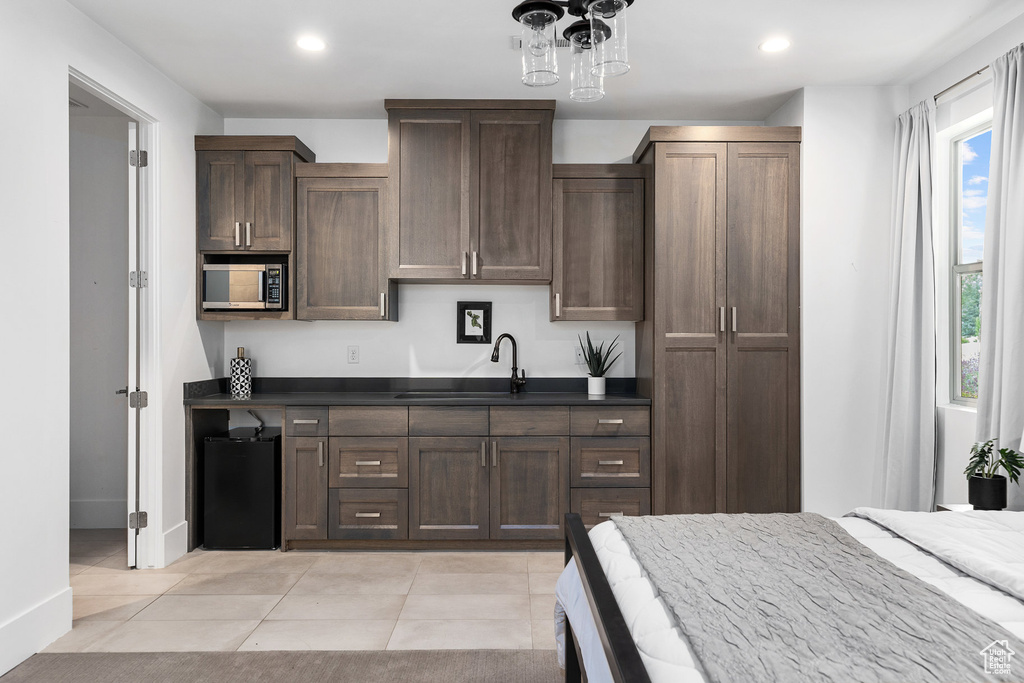 Kitchen featuring stainless steel microwave, dark countertops, recessed lighting, light tile patterned flooring, and dark brown cabinetry