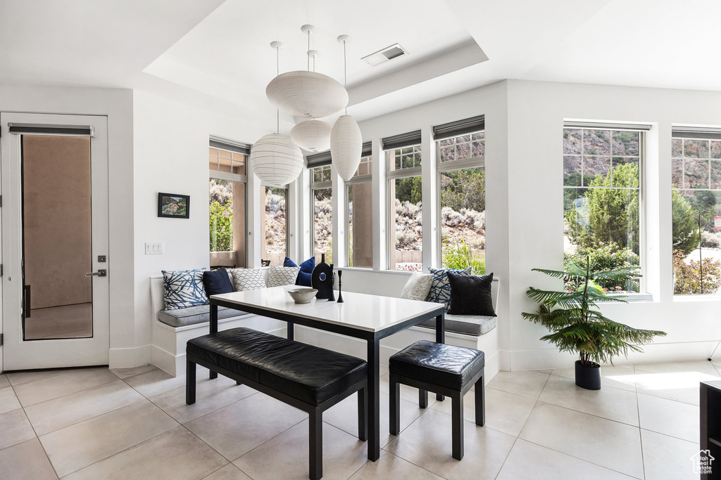 Dining room with a tray ceiling and light tile patterned floors