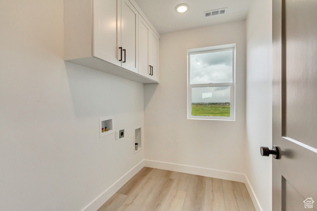 Washroom with cabinet space, light wood-style floors, hookup for an electric dryer, hookup for a washing machine, and recessed lighting