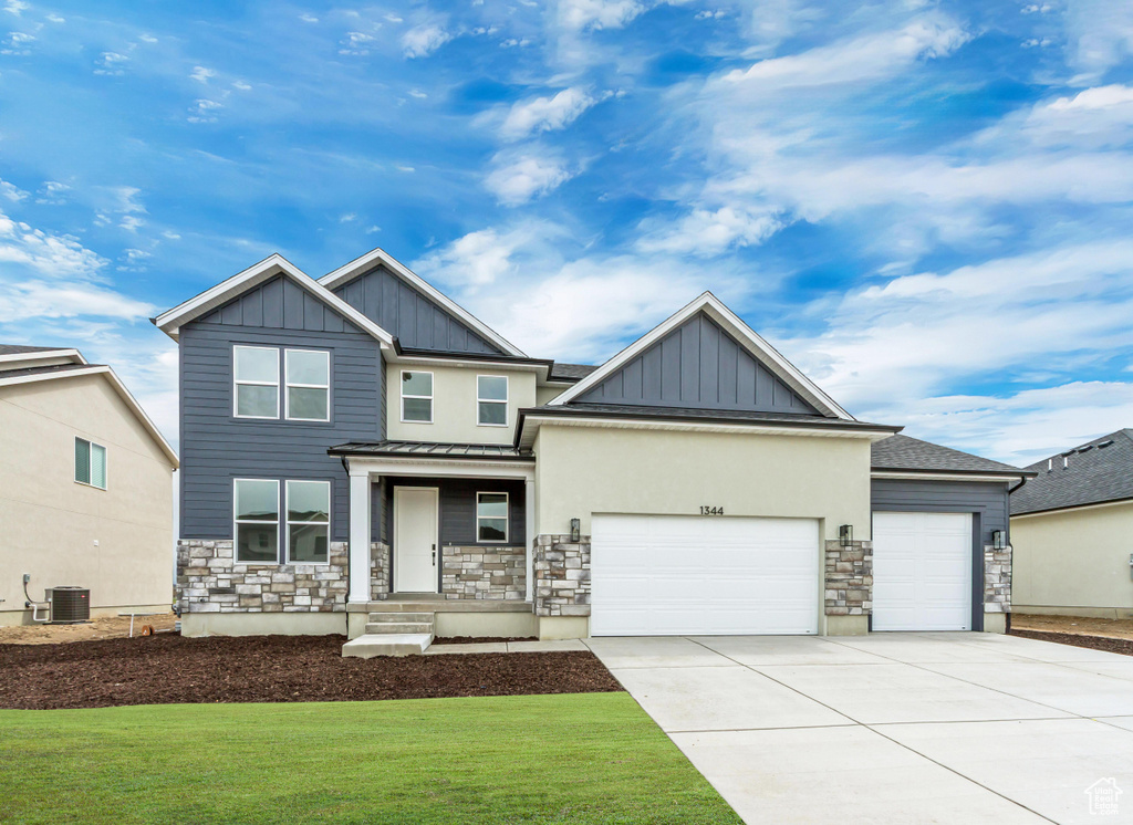 Craftsman-style home featuring board and batten siding, a garage, stone siding, concrete driveway, and a front yard