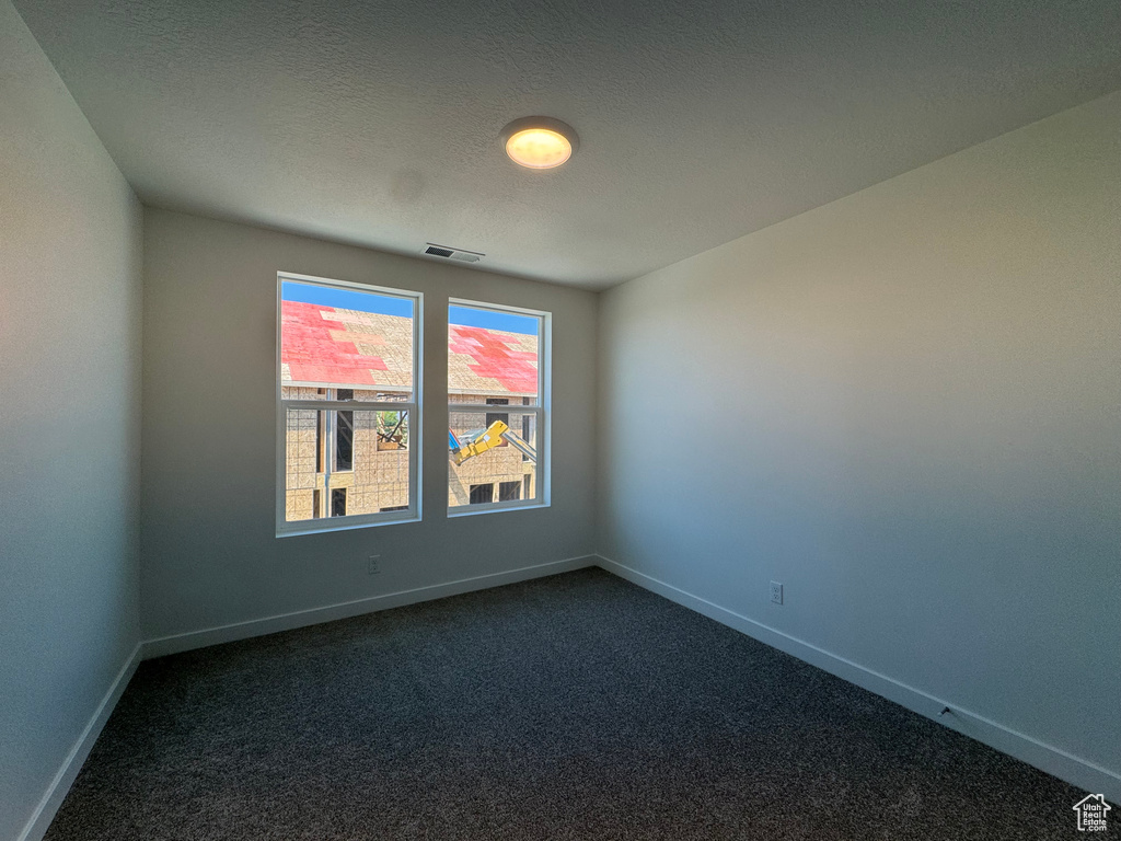 Unfurnished room with dark colored carpet and baseboards