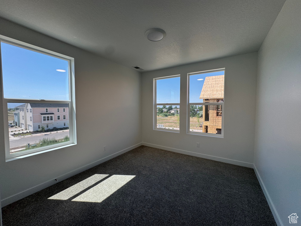 Spare room with dark colored carpet and baseboards