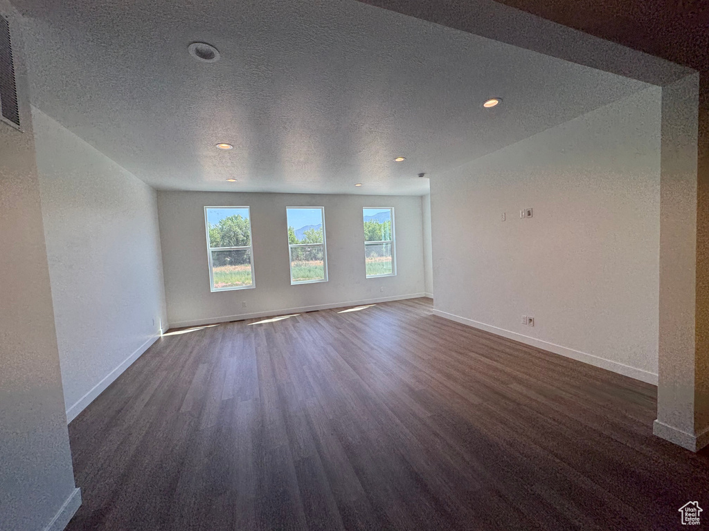 Unfurnished room featuring dark wood finished floors, recessed lighting, and a textured ceiling