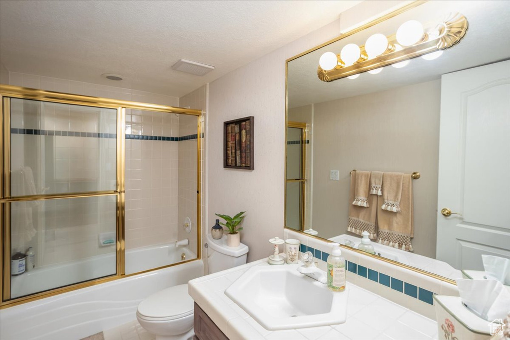 Full bath featuring vanity and shower / bath combination with glass door