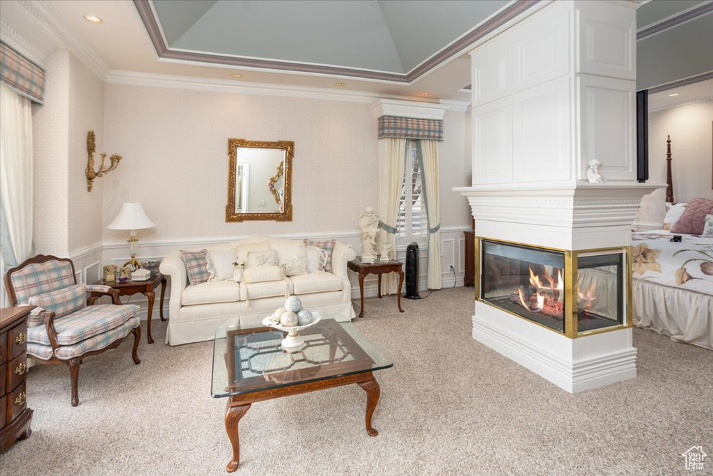 Living room featuring ornamental molding, light colored carpet, a wainscoted wall, and a multi sided fireplace