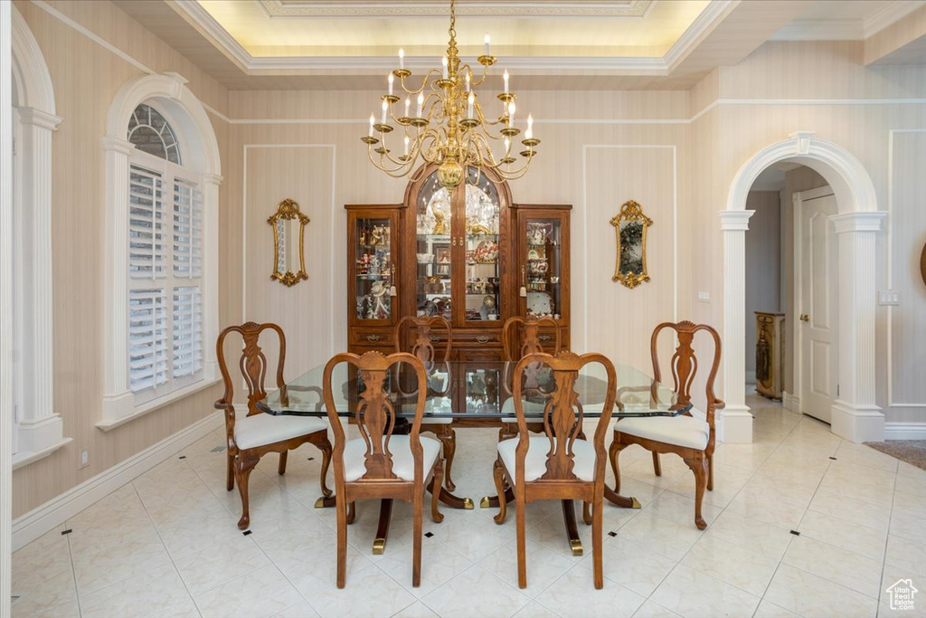 Dining area with a chandelier, arched walkways, crown molding, a raised ceiling, and light tile patterned floors