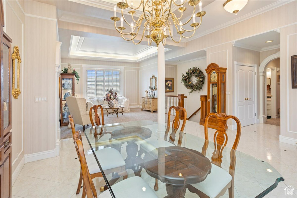 Dining space with ornamental molding, arched walkways, a chandelier, light tile patterned floors, and a decorative wall