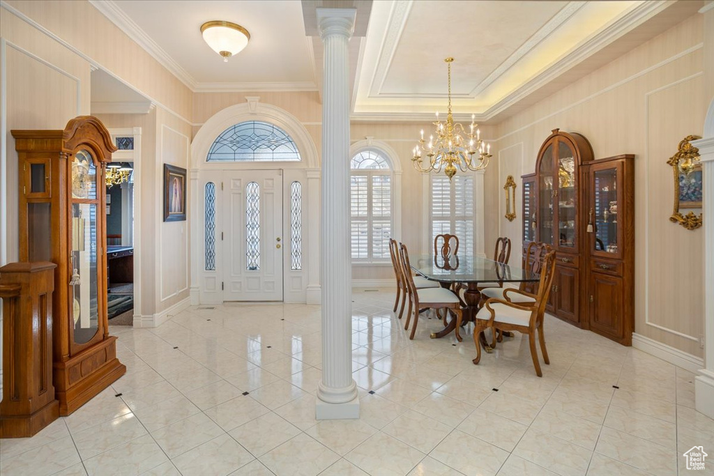 Foyer entrance with a decorative wall, ornamental molding, ornate columns, a chandelier, and light tile patterned floors
