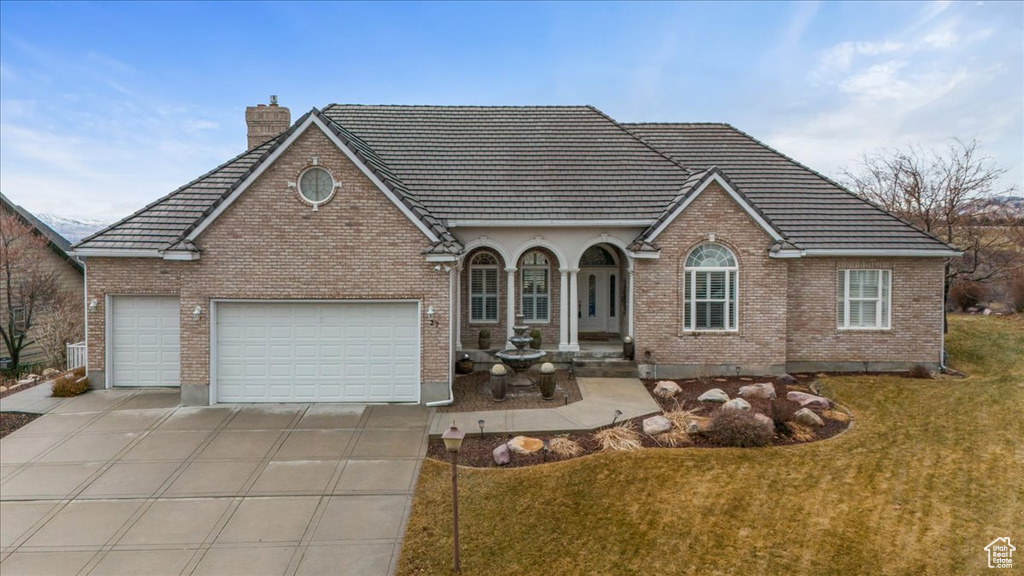 View of front of home featuring driveway, a front lawn, and brick siding