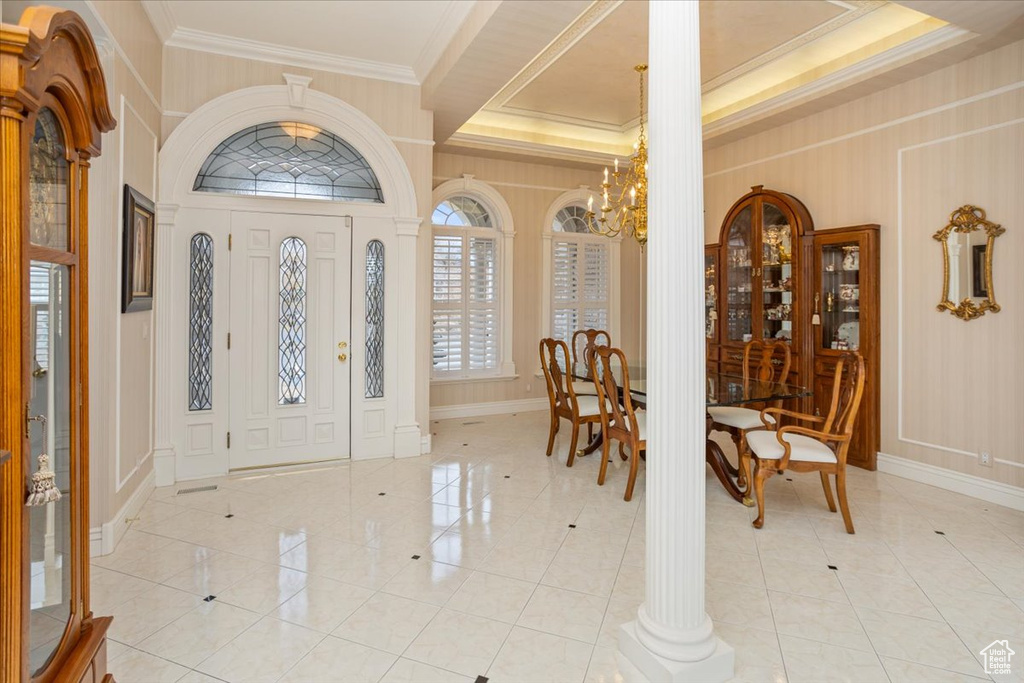 Foyer entrance featuring a chandelier, crown molding, light tile patterned floors, and a decorative wall