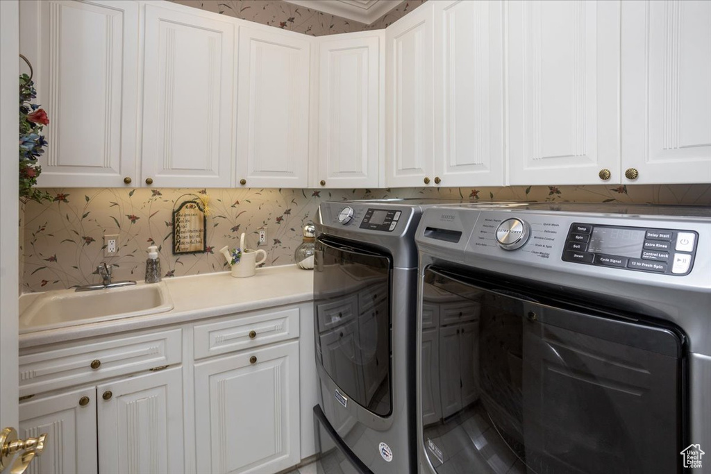 Laundry area with cabinet space, independent washer and dryer, and wallpapered walls