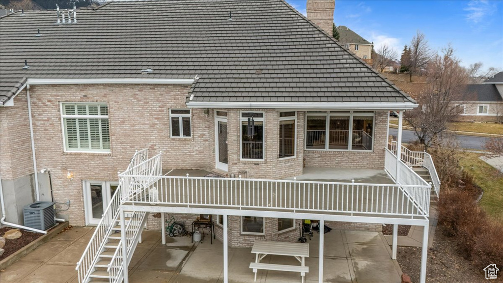 Back of property featuring stairs, a patio area, brick siding, and a tile roof