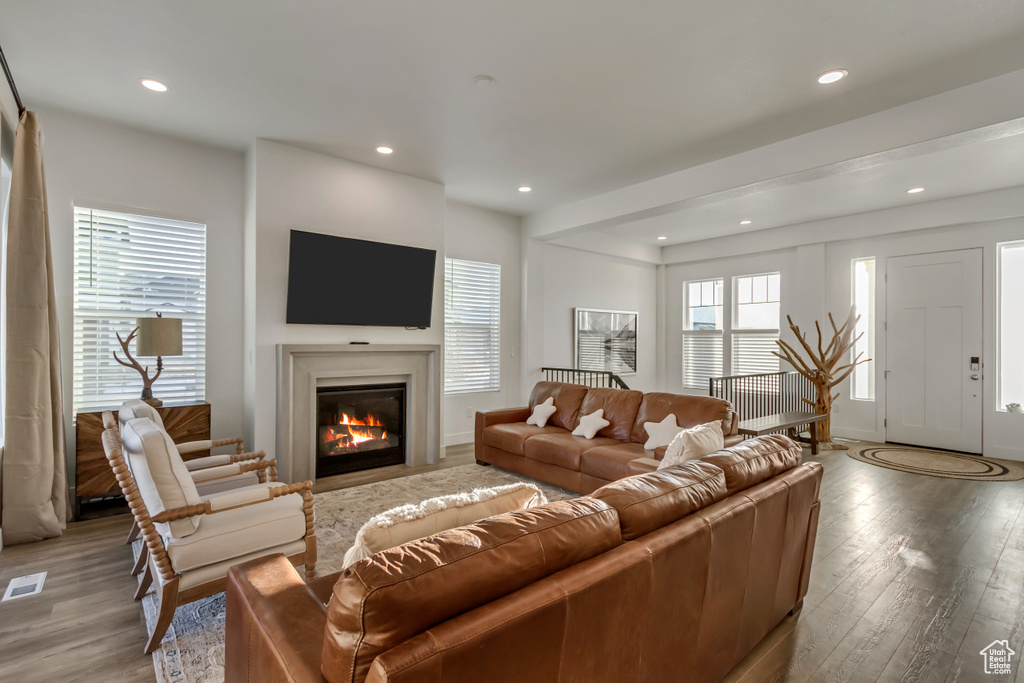 Living area with light wood-style floors, recessed lighting, and a glass covered fireplace