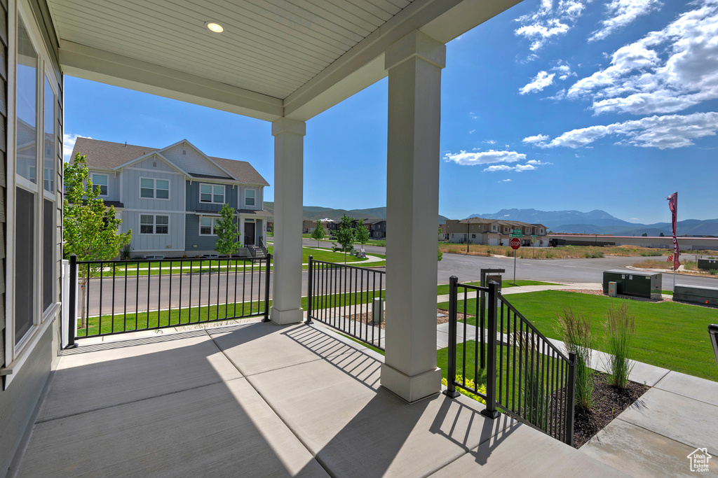 Covered porch with a mountain view, a residential view, and a yard