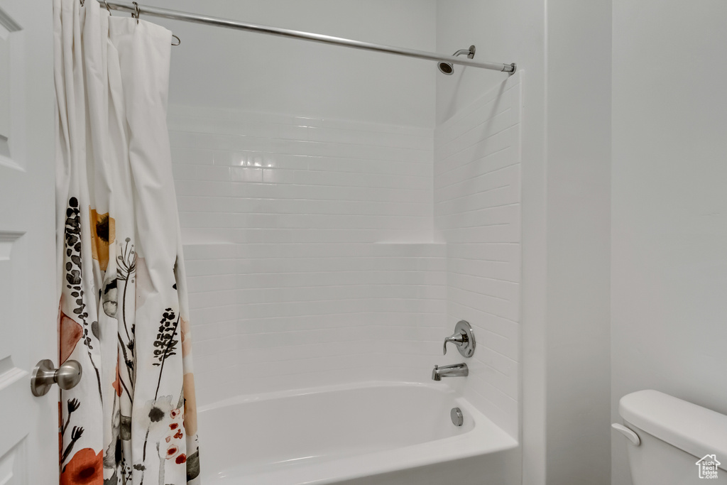 Bathroom featuring toilet and shower / bath combo with shower curtain