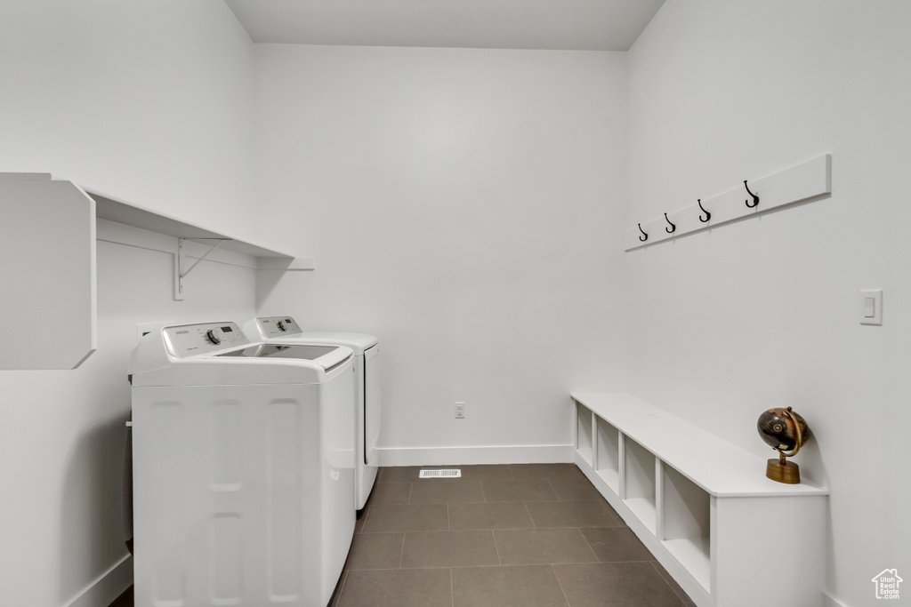Washroom featuring washing machine and dryer and dark tile patterned floors
