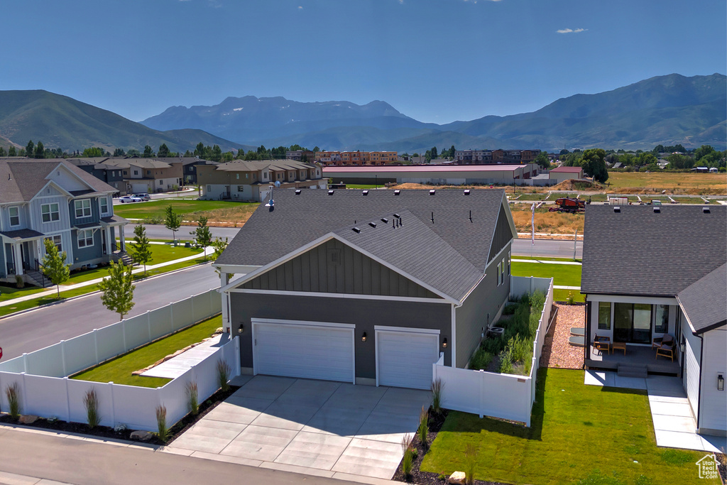 View of front of property featuring concrete driveway, board and batten siding, a garage, a mountain view, and a shingled roof