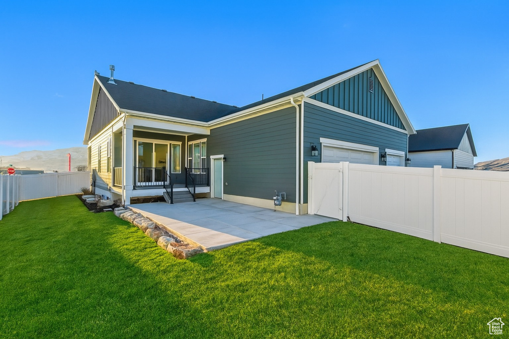 Rear view of property featuring board and batten siding, a fenced backyard, a patio area, a mountain view, and an attached garage