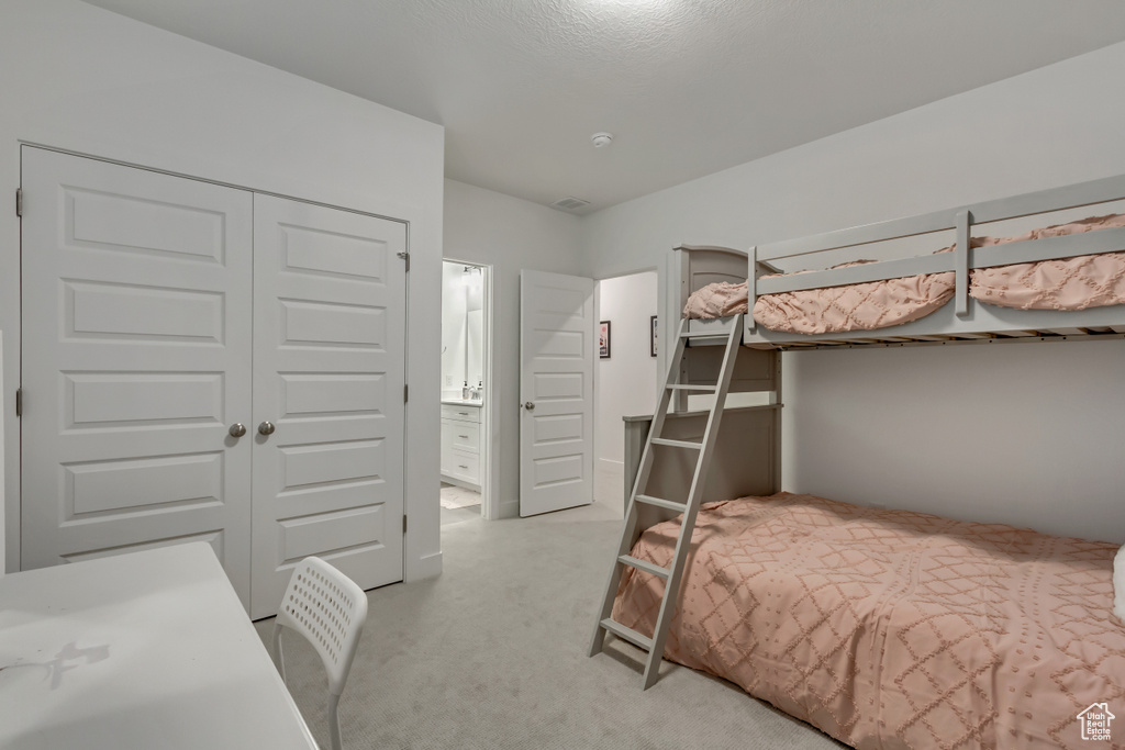 Bedroom featuring light colored carpet, connected bathroom, and a closet