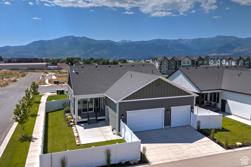 View of front of home featuring board and batten siding, an attached garage, a fenced backyard, and a mountain view