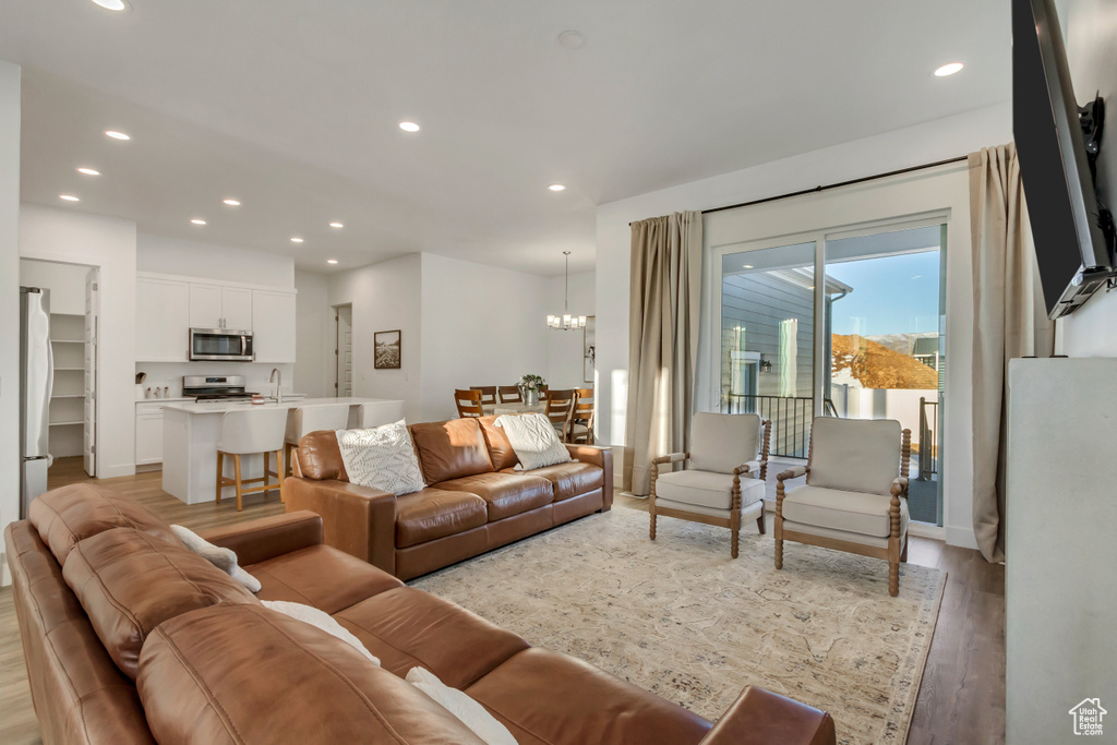 Living area with light wood finished floors, recessed lighting, and a chandelier