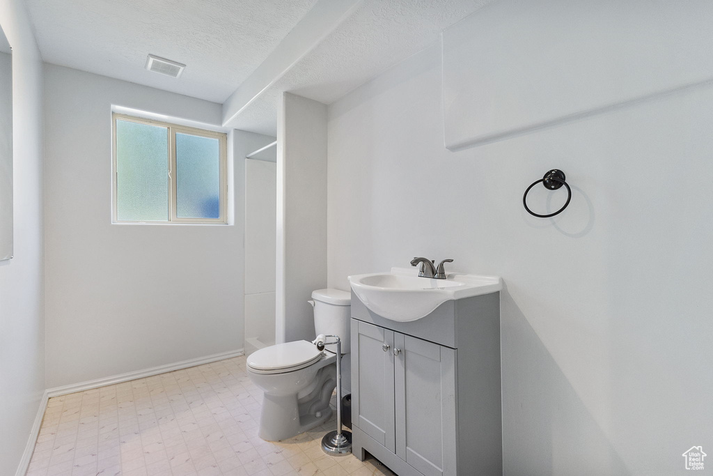 Bathroom featuring a shower, vanity, tile patterned floors, and a textured ceiling