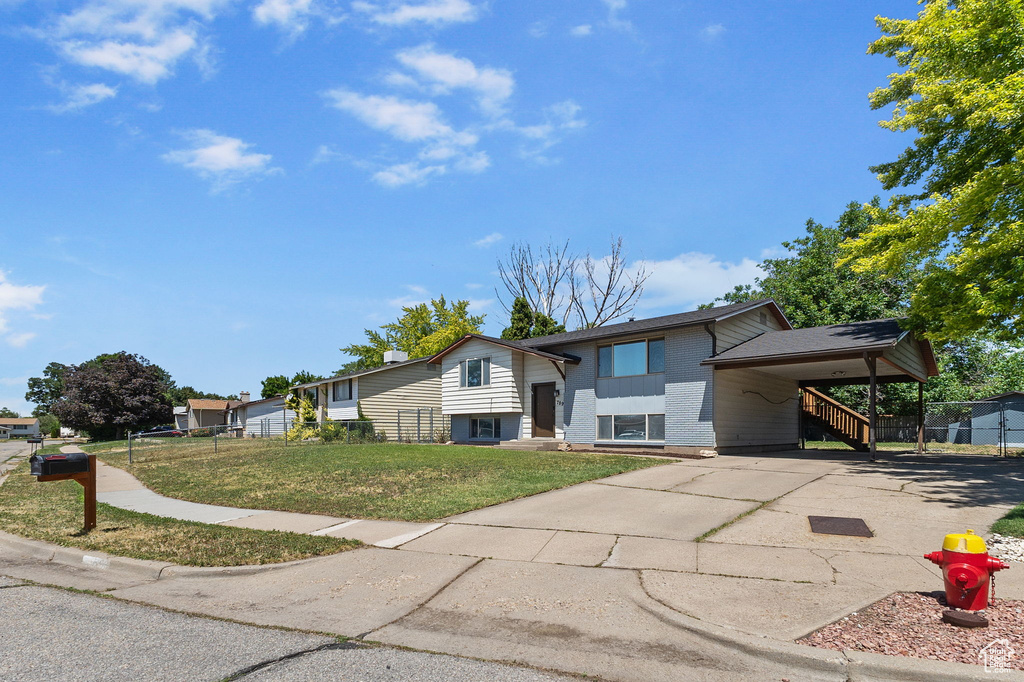 Raised ranch with concrete driveway, brick siding, and a carport