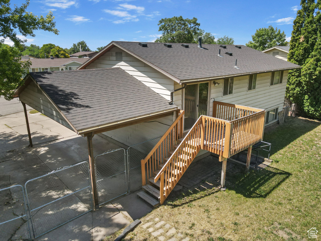 Rear view of property featuring a shingled roof, a yard, a wooden deck, and stairway