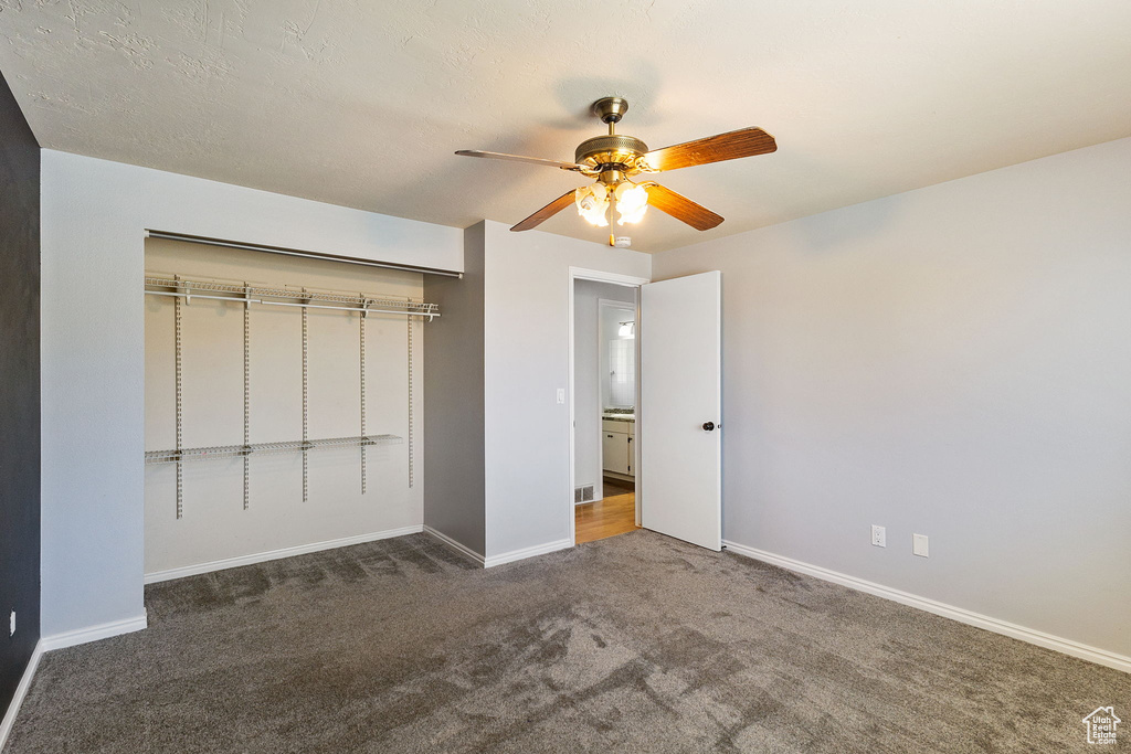 Unfurnished bedroom with carpet, a closet, and a ceiling fan