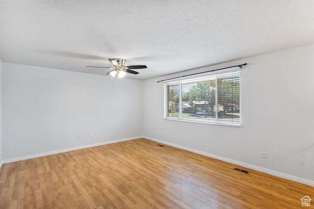 Empty room with light wood-style flooring, a ceiling fan, and a textured ceiling