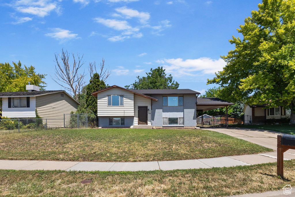 Raised ranch featuring concrete driveway, a carport, and brick siding