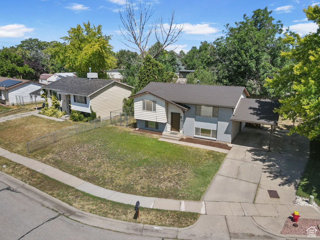 Bi-level home featuring driveway, an attached carport, entry steps, a chimney, and brick siding