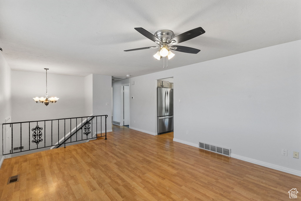 Unfurnished room featuring light wood-style flooring, a chandelier, and ceiling fan