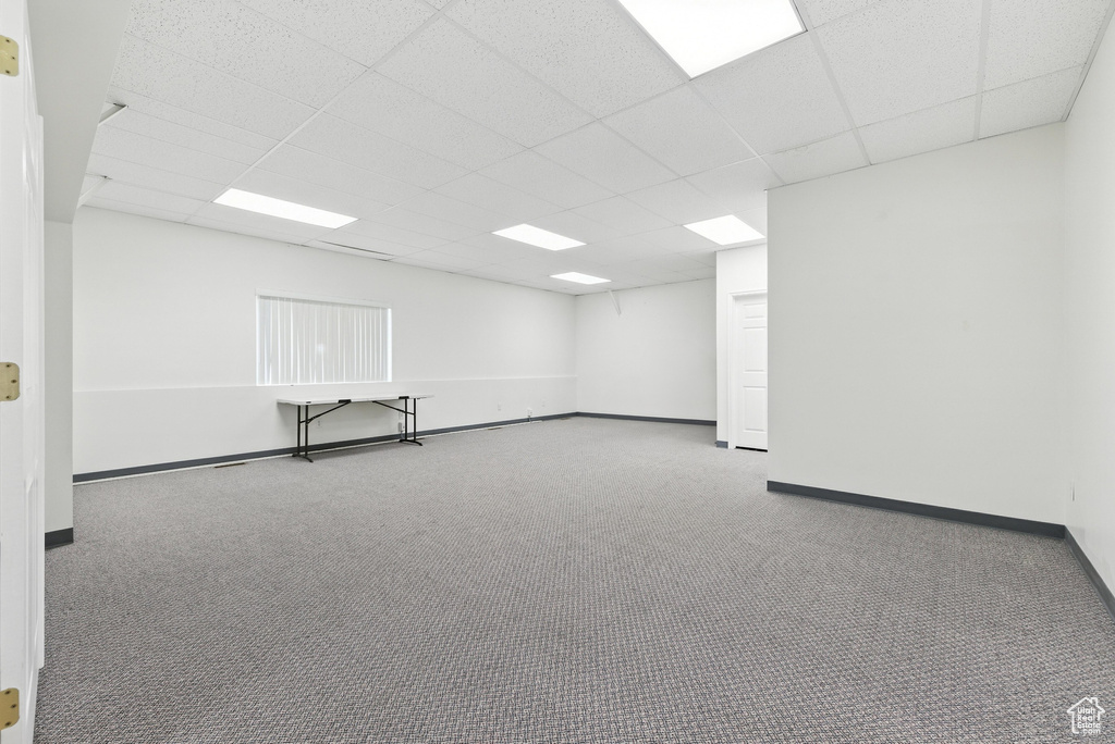 Empty room with a drop ceiling and carpet flooring