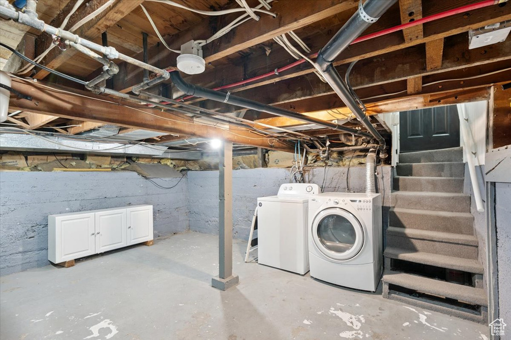 Unfinished below grade area with washer and clothes dryer and stairway